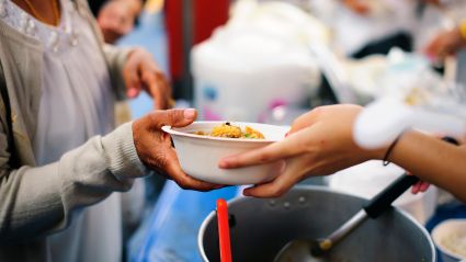 An image of someone's hands, handing over a bowl of food to another person's hands.