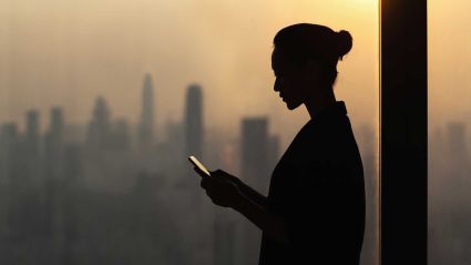 An image of a woman's silhouette wearing a bun and looking at her phone against a city skyline background, leading to an article titled "Global Insights: Opportunities for Government and Business to Advance Mental Health'.